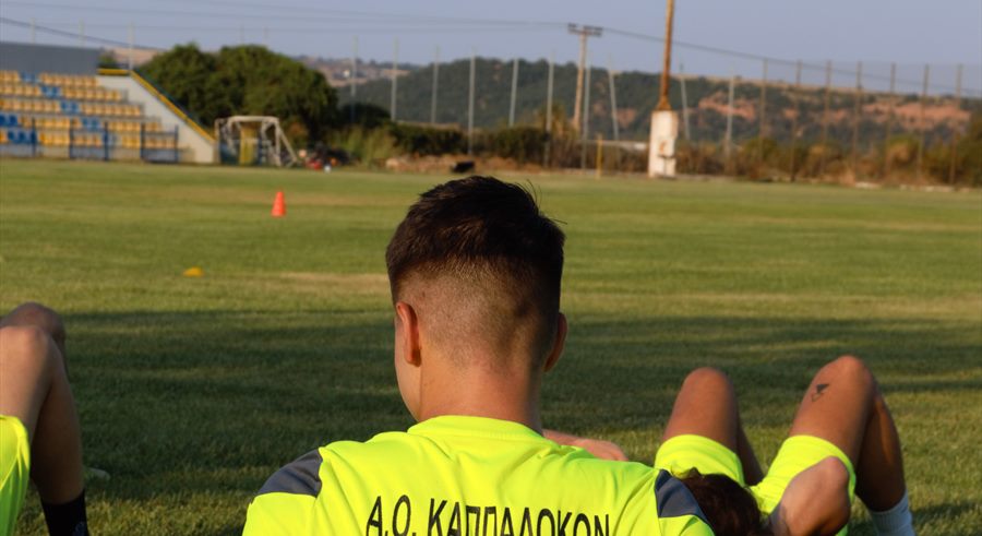 Αθλητές του Α.Ο. Καππαδοκών σε διατάσεις στο γήπεδο, με τις εξέδρες στο βάθος